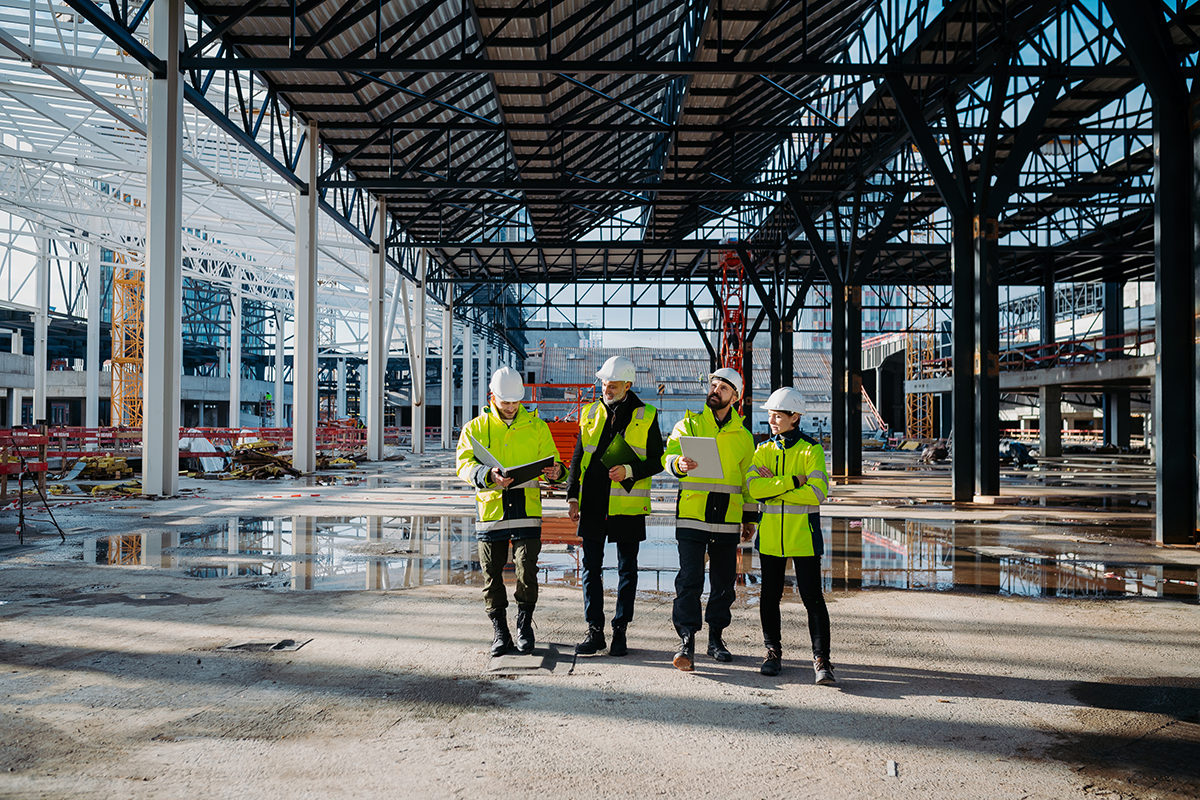 Four contractors walk through a construction site
